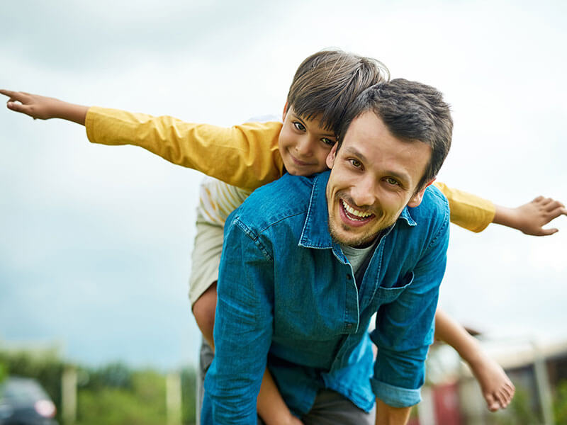 father and young son smiling together outdoors